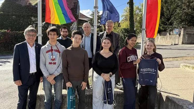 Graz: Gruppe von neun Personen mit Regenbogen- und EU-Fahnen im Hintergrund.