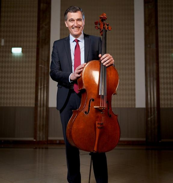 Cellist Heinrich Schiff mit seinem Instrument in einem Konzertsaal